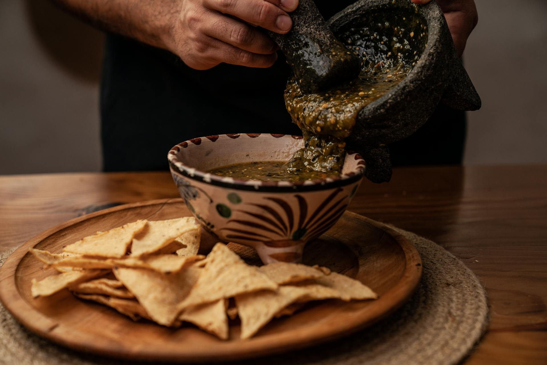 Person Pouring Salsa in a Ceramic Bowl